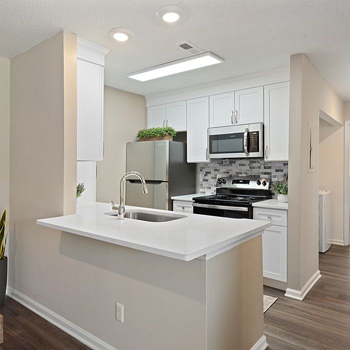 Contemporary kitchen with sleek white cabinetry, modern appliances, and a stylish breakfast bar.