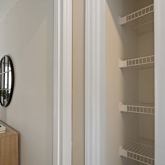 Bright and spacious hallway featuring a sleek wall mirror and open shelving for abundant storage options.