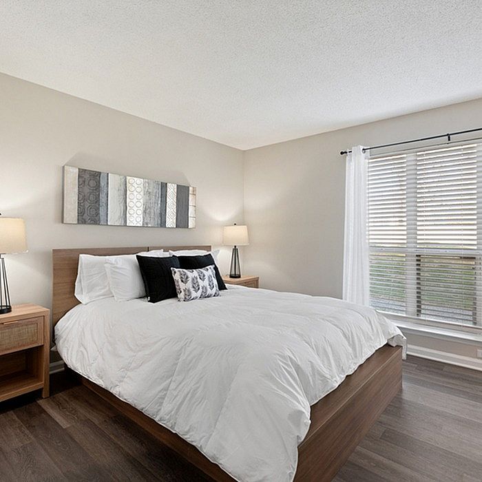 Bright and inviting bedroom with a plush bed, chic decor, and large sunlit window.