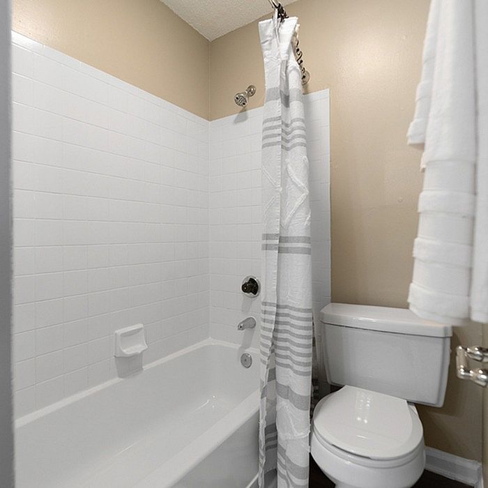 Modern bathroom featuring a pristine white tub, stylish shower curtain, and contemporary toilet in a clean, inviting setting.