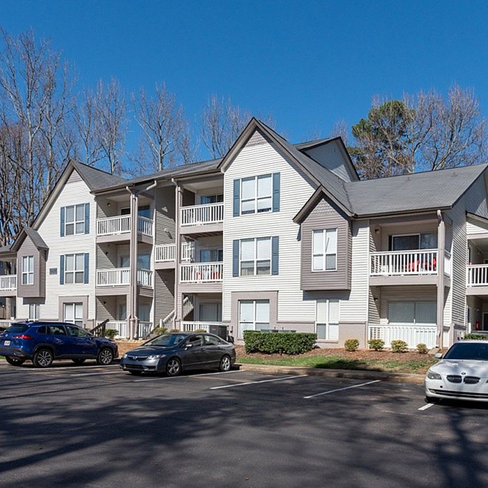 Charming multi-story apartment building with balconies and ample parking in a serene neighborhood setting.