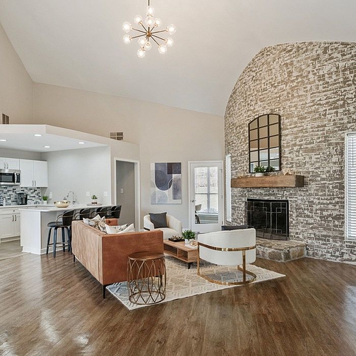 Chic living space with modern open-concept kitchen, stylish seating area, and rustic brick fireplace accent wall.