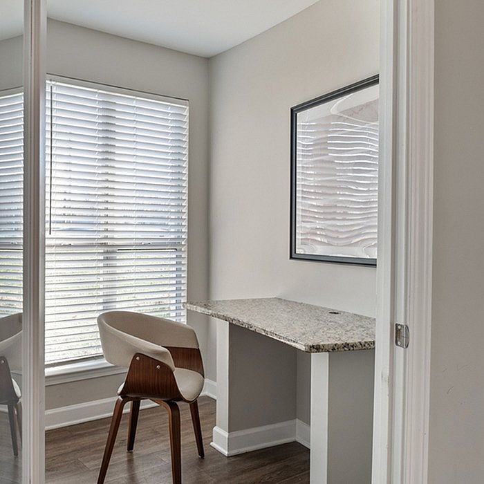 Chic home office nook with granite countertop and designer chair, illuminated by natural light through elegant blinds.