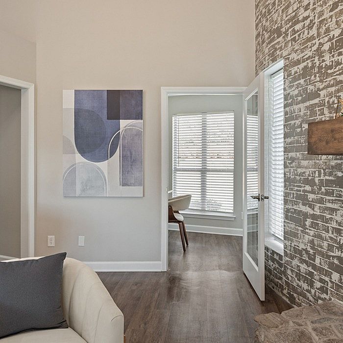 Inviting apartment living area with stylish decor, modern artwork, and a well-lit room with wooden flooring.