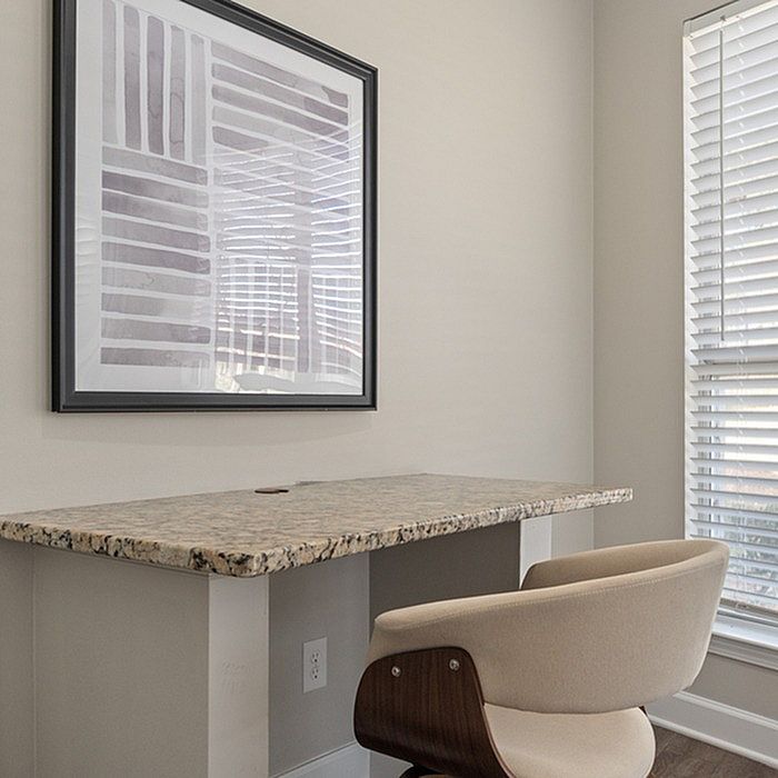 Bright home office corner featuring a sleek granite desk, modern art, and abundant natural light through large windows.