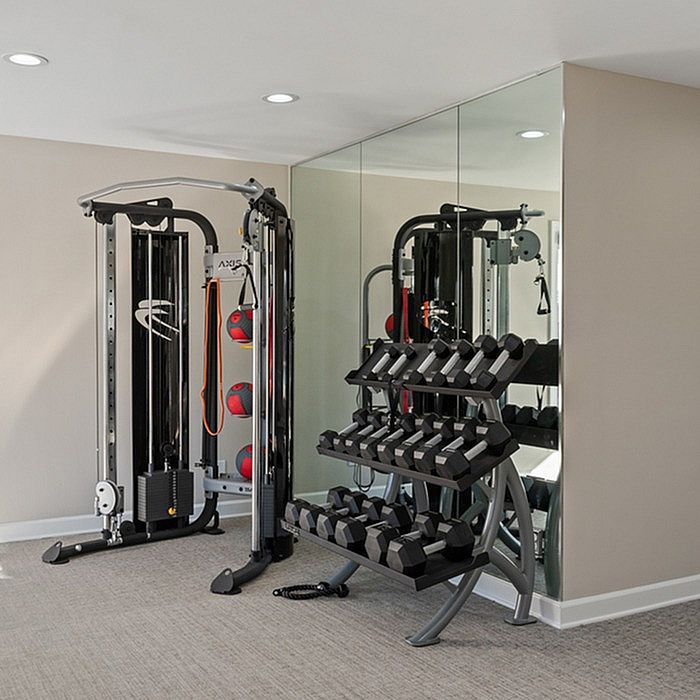 Modern in-home gym with state-of-the-art exercise equipment, sleek mirrors, and a range of free weights for an optimal workout experience.
