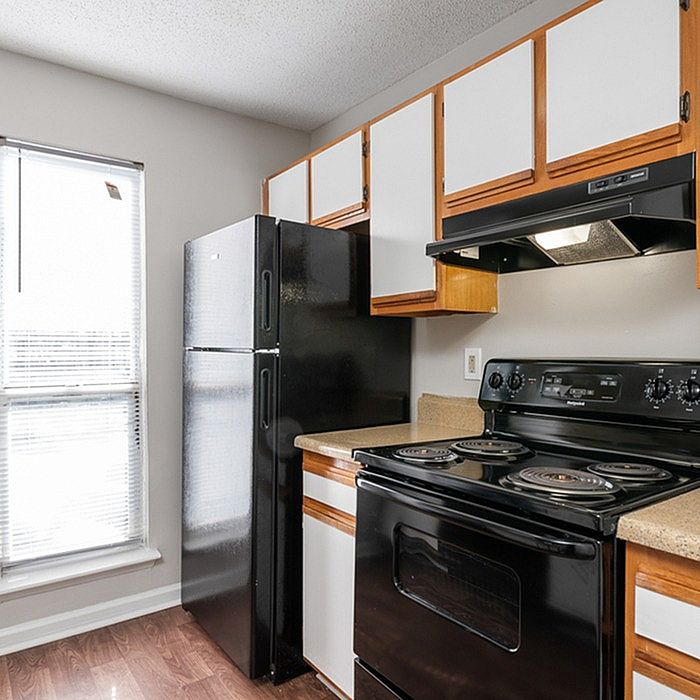 Charming kitchen with modern black appliances, abundant natural light, and sleek wooden cabinetry.