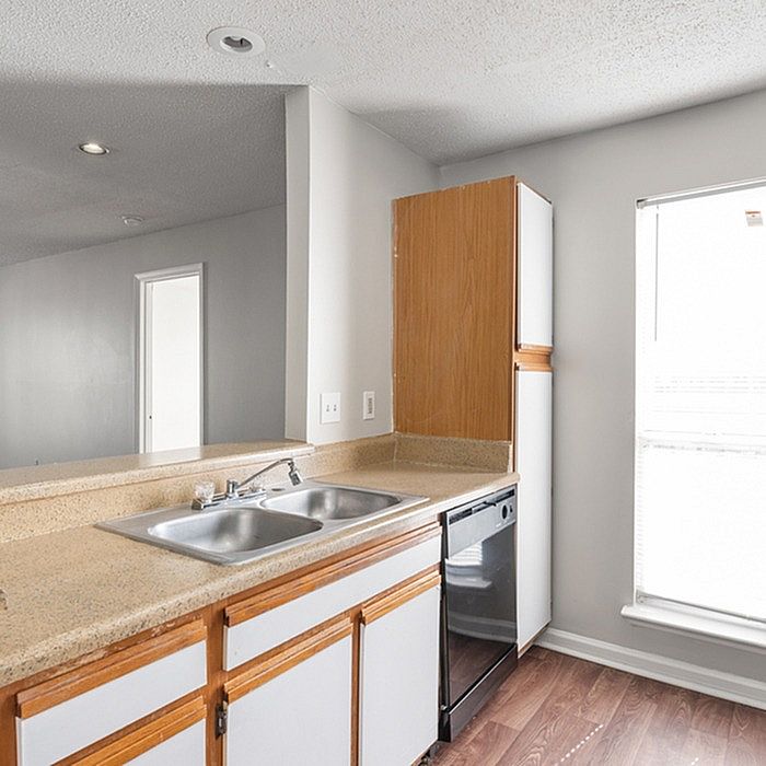 Bright kitchen showcasing modern countertops, sleek double sink, and efficient cabinetry with natural light pouring through the window.