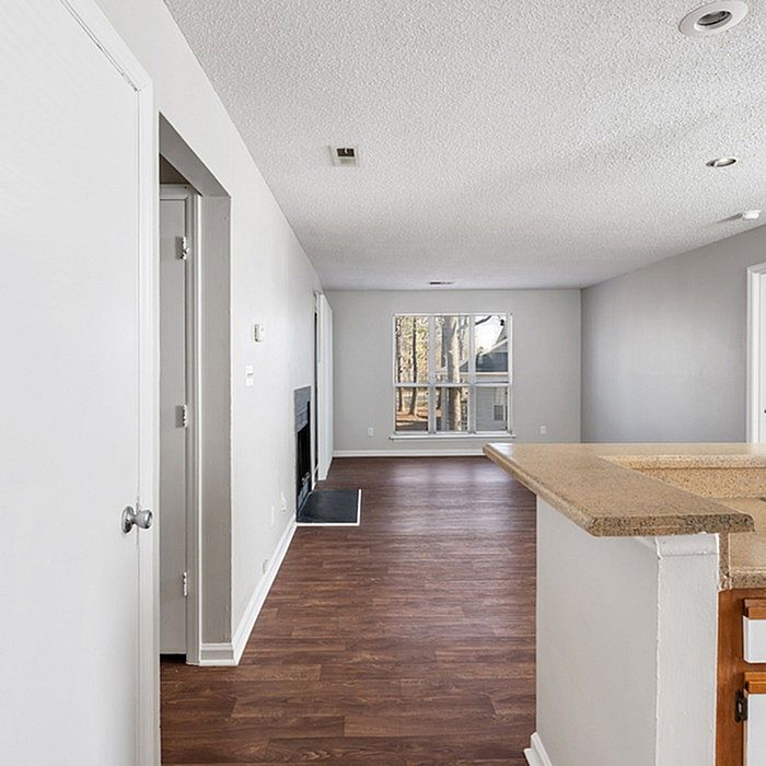 Inviting open-plan living area with hardwood floors, cozy fireplace, and abundant natural light through large windows.