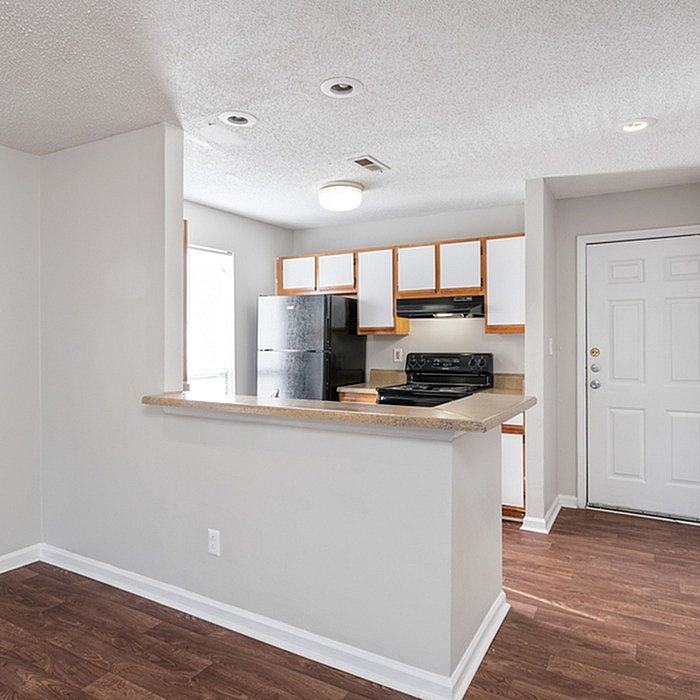 Bright and modern kitchen with sleek black appliances, cozy breakfast bar, and stylish wood flooring.