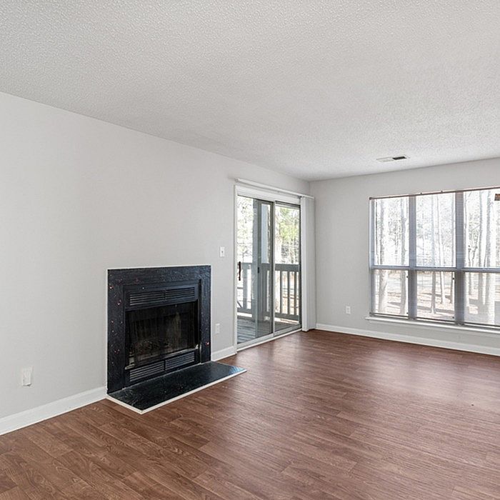 Bright and airy living room with elegant hardwood floors, a cozy fireplace, and sliding glass doors leading to a serene balcony.