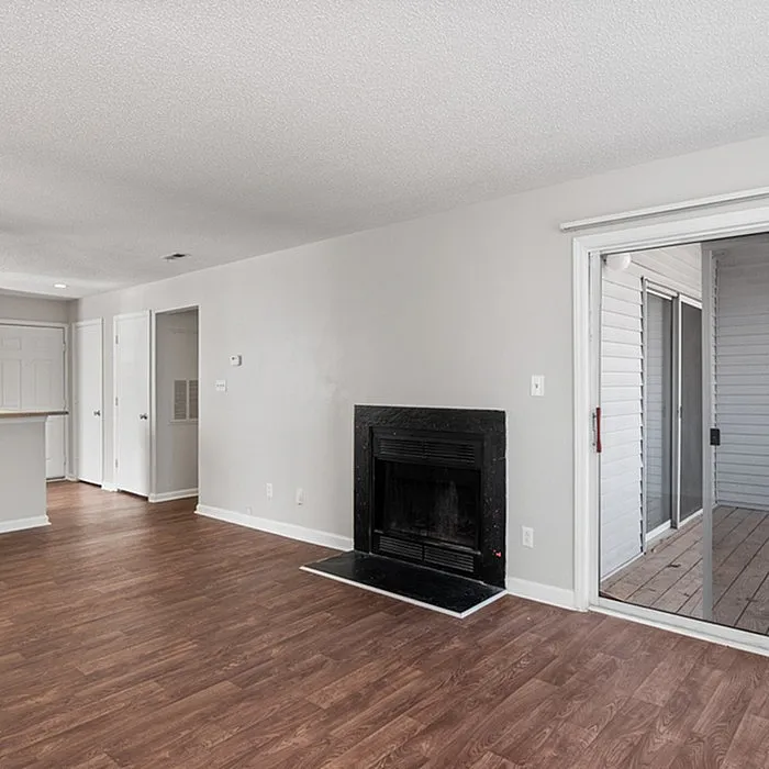 Inviting living room with elegant wood flooring, a cozy fireplace, and sliding glass doors leading to a private patio.