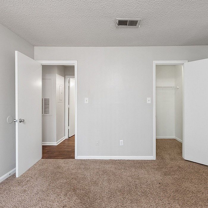 Bright bedroom with plush carpet, closet space, and inviting neutral walls, perfect for personalization.