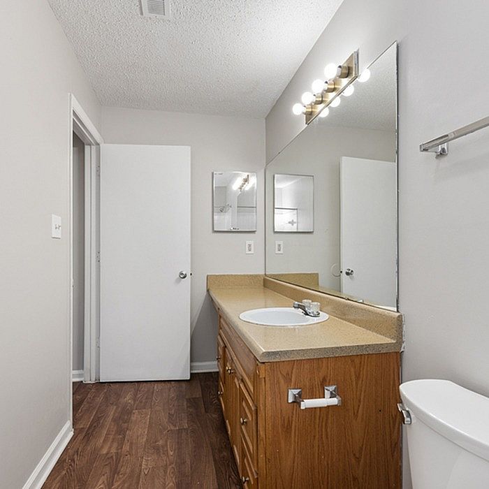 Modern bathroom with sleek wooden cabinetry, elegant countertop, and large mirror reflecting chic lighting.