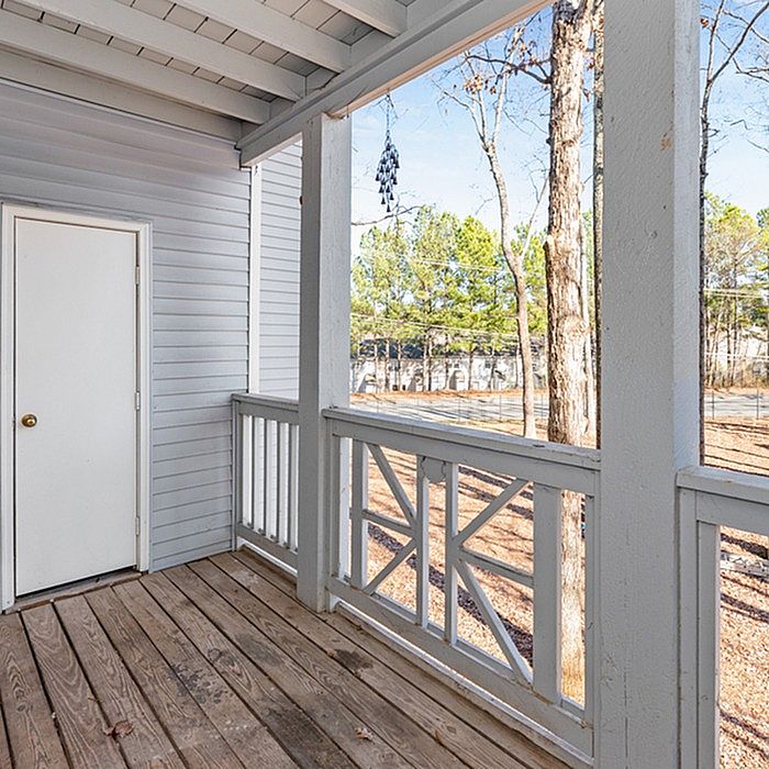 Charming apartment balcony with rustic wooden decking and serene forest views.