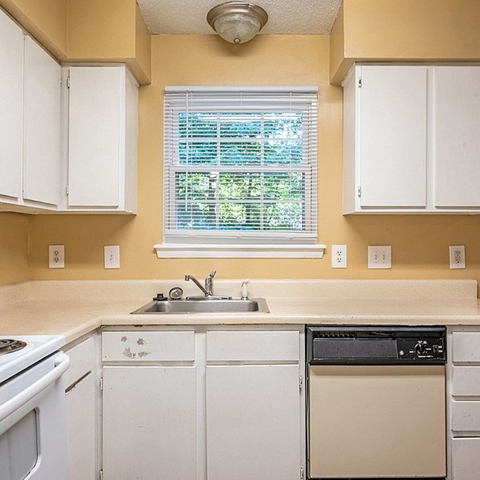 Cozy kitchen with warm beige walls, white cabinetry, and a double sink beneath a bright window.