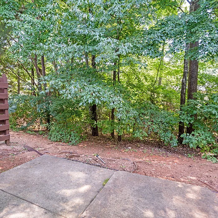 Serene apartment patio retreat with lush green trees providing a natural, calming backdrop.