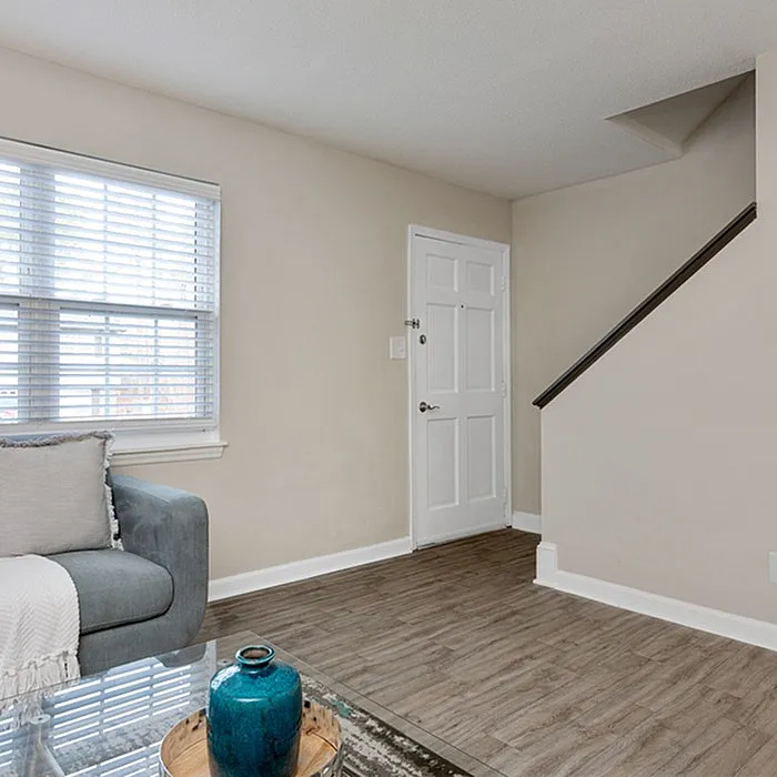 Bright entryway featuring elegant wood flooring, a stylish staircase, and a welcoming living space with modern decor.