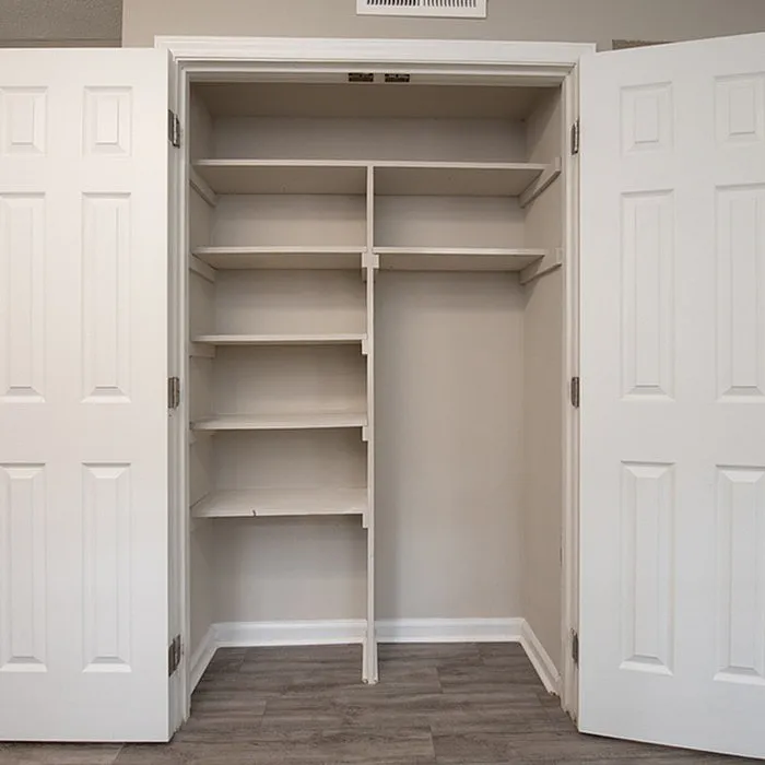 Spacious built-in closet with elegant white double doors and ample shelving, perfect for organized storage.