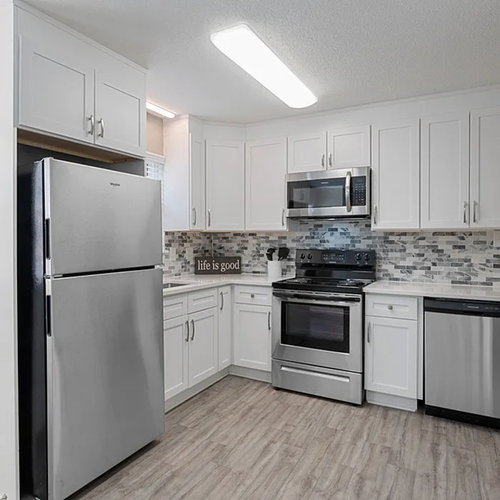 Modern kitchen with sleek stainless steel appliances, chic white cabinetry, and elegant tile backsplash.