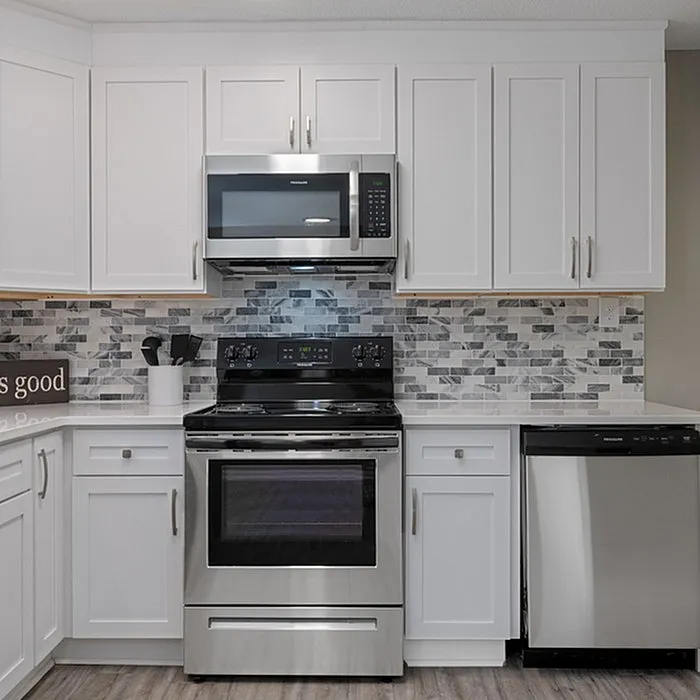 Modern kitchen with sleek stainless steel appliances, elegant white cabinetry, and stylish mosaic backsplash.