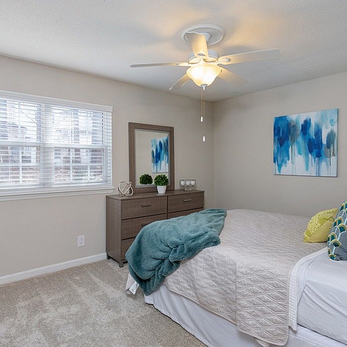 Cozy bedroom featuring a comfortable bed with stylish pillows, elegant dresser with a mirror, and vibrant abstract wall art.