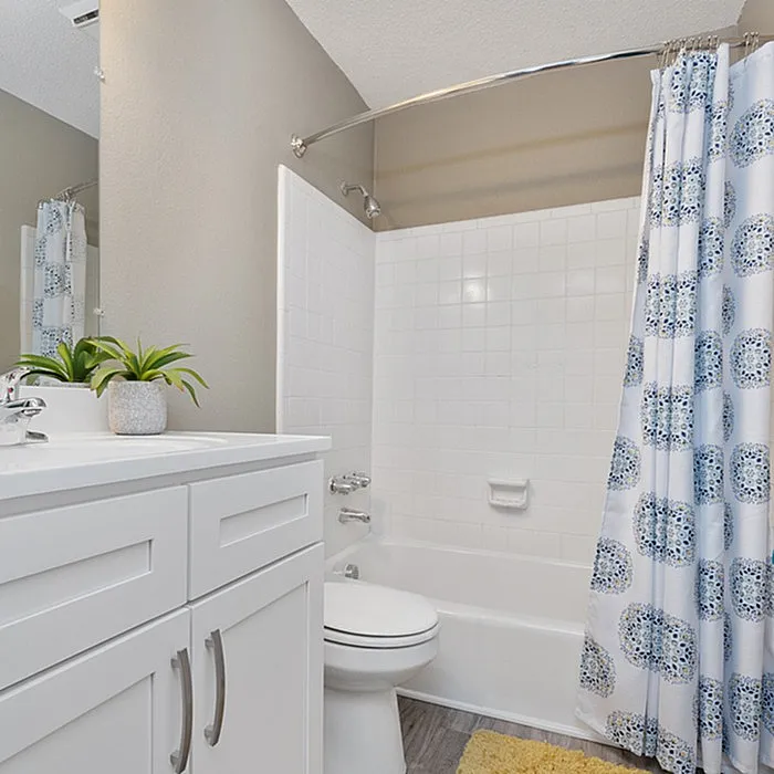 Bright and modern bathroom with elegant white vanity, chic shower curtain, and a touch of greenery for a refreshing ambiance.