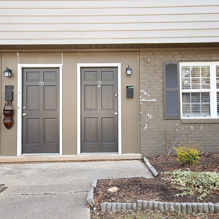 Charming apartment entrance with twin black doors, elegant lighting, and inviting window shutters, perfect for cozy urban living.