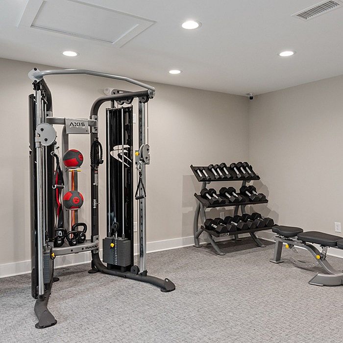 Modern fitness room equipped with a versatile exercise machine, complete dumbbell set, and sleek workout bench in a bright and inviting space.