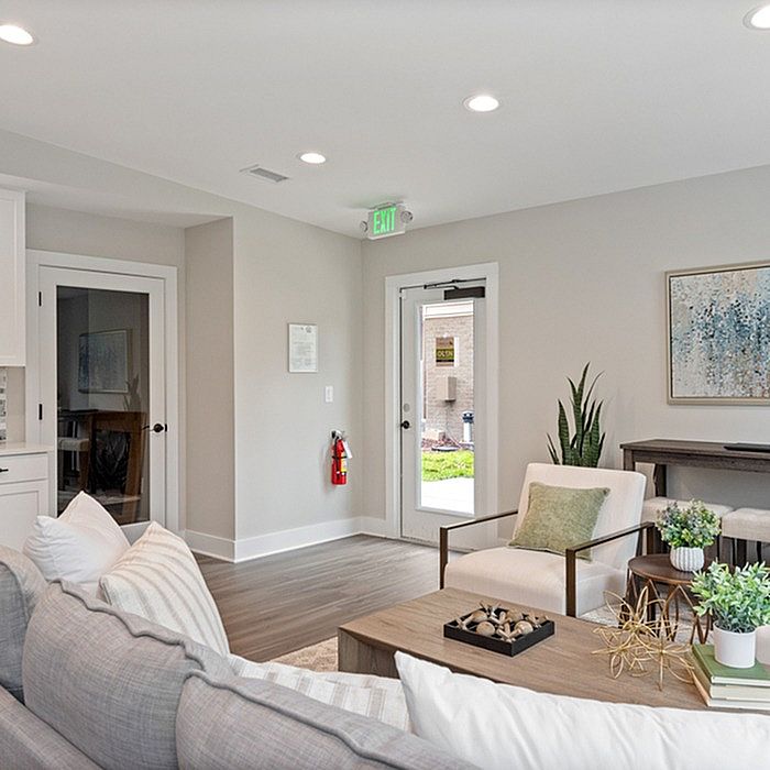 Modern living room with stylish decor, featuring comfortable seating, artistic wall accents, and natural light from a glass door, creating an inviting atmosphere.