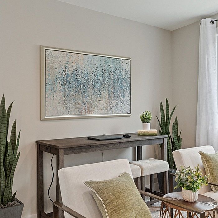 Elegant apartment corner with a chic console table, abstract art, and cozy seating accented by lush green plants.