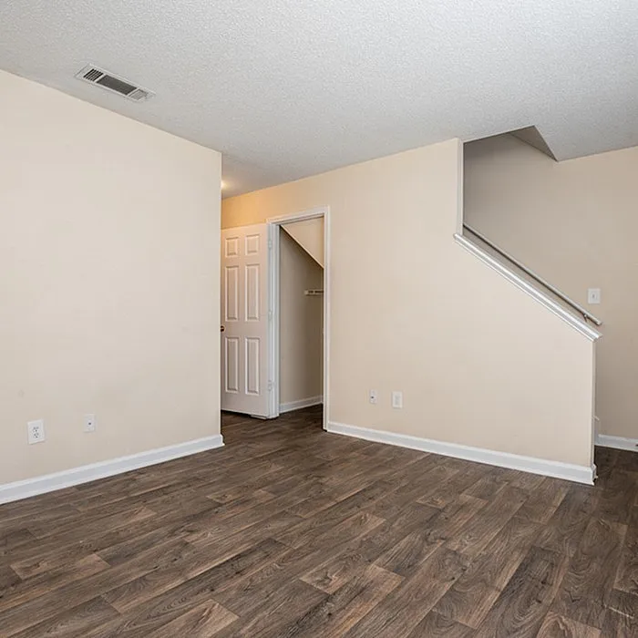 Inviting room with elegant hardwood floors, neutral walls, and a stylish doorway leading to a cozy space perfect for versatile living.