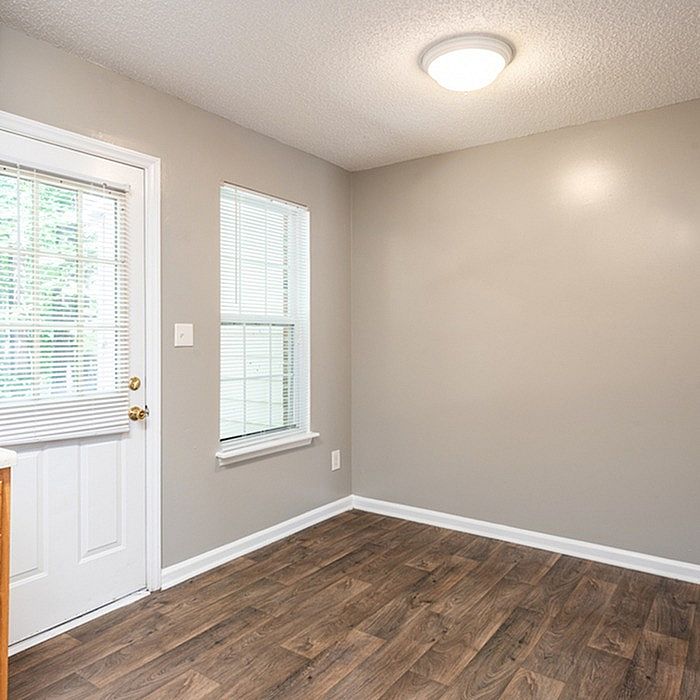 Bright room with elegant hardwood floors, neutral walls, and ample natural light from large windows, perfect for cozy living space.