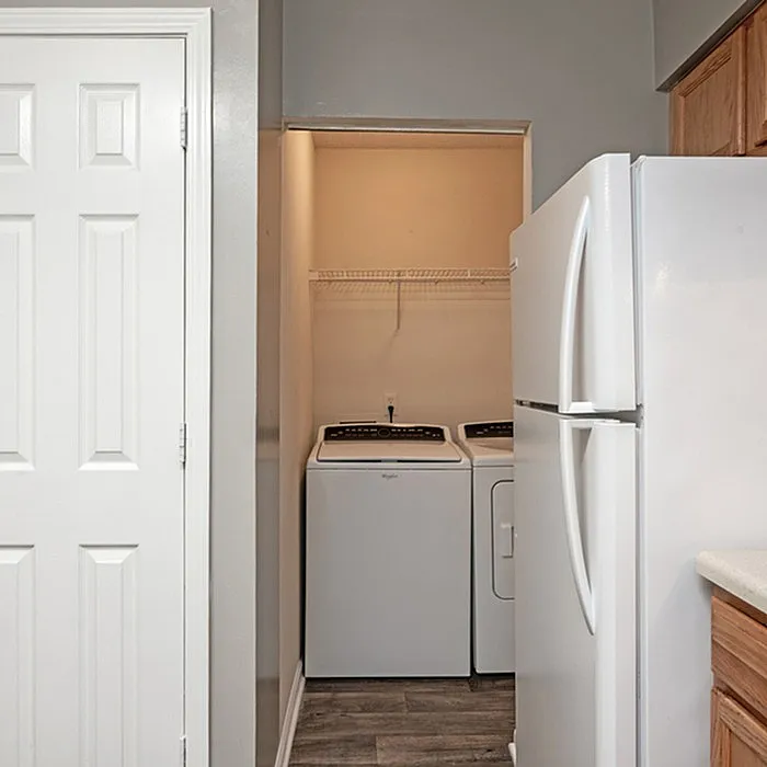 Contemporary laundry nook with washer and dryer, adjacent to a modern kitchen with sleek refrigerator.