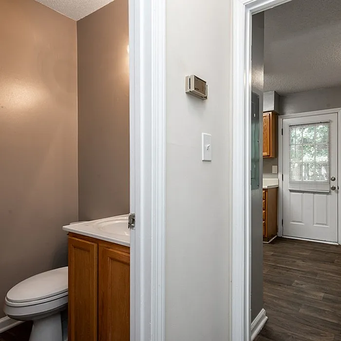 Inviting apartment featuring a cozy bathroom with modern fixtures, leading to a bright kitchen area with a door opening to natural light.