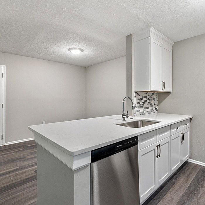 Modern kitchen with sleek white cabinetry and stainless steel appliances, featuring contemporary backsplash and polished quartz countertops.
