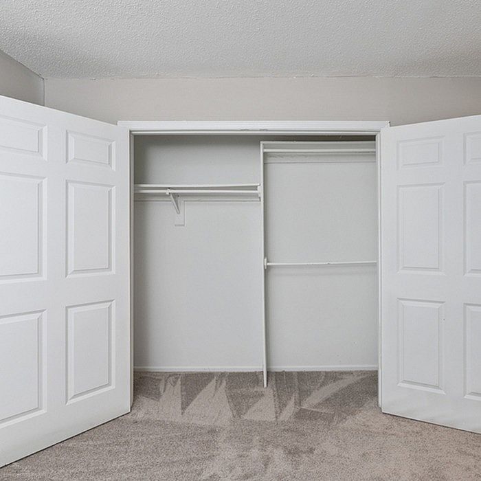 Spacious and modern walk-in closet with white double doors and sleek interior shelving, perfect for organized living.
