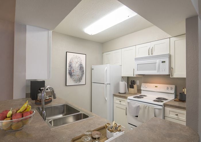 Modern kitchen with sleek countertops, stainless steel appliances, and stylish white cabinetry, perfect for culinary enthusiasts.