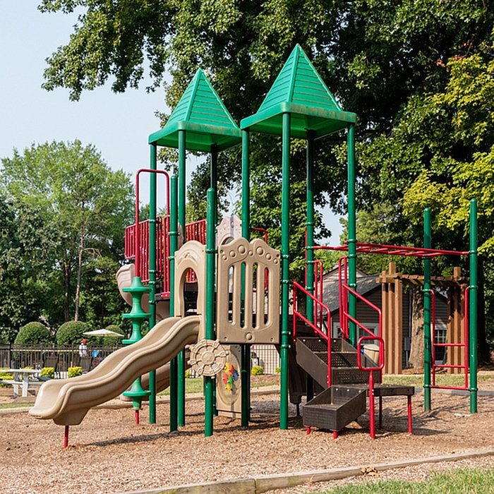 Charming playground with colorful slides and climbing structures, surrounded by lush greenery, ideal for family-friendly living.