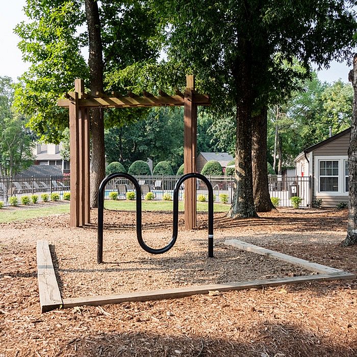 Charming outdoor space with bike rack, wooden pergola, and lush greenery, perfect for relaxation and nature lovers.