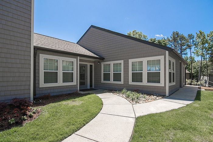 Charming modern home exterior with a welcoming path, lush greenery, and elegant architectural details.