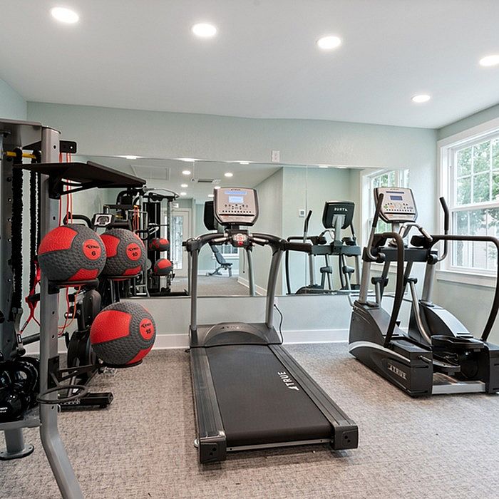 Modern fitness room featuring state-of-the-art treadmills, exercise bike, and vibrant medicine balls under bright lighting.