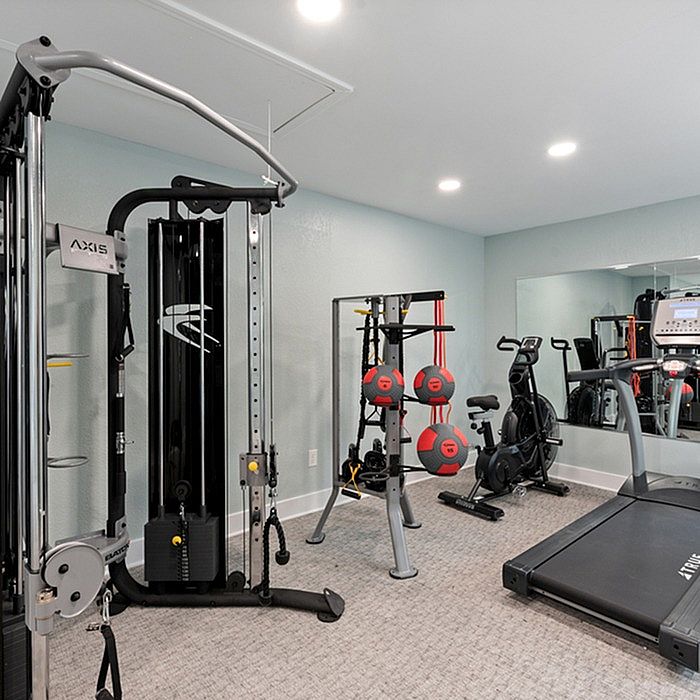 Modern apartment gym featuring cutting-edge fitness equipment, including a treadmill, exercise bike, and weight machine for a complete workout experience.