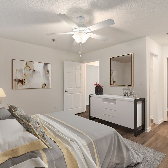 Elegant bedroom with modern decor, featuring a cozy bed with stylish linens, a sleek white dresser, and tasteful artwork, all under a bright ceiling fan.