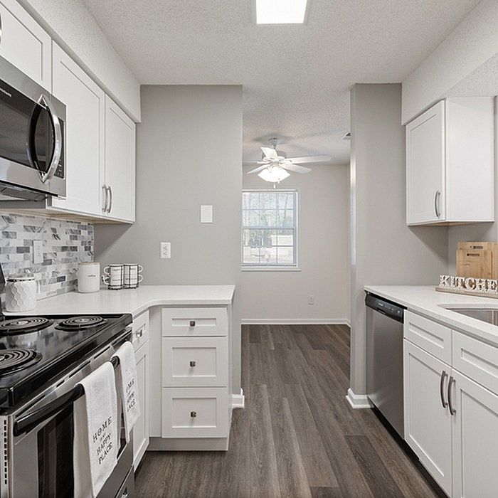 Modern kitchen with sleek white cabinetry, stainless steel appliances, and elegant gray flooring, perfect for culinary creativity.