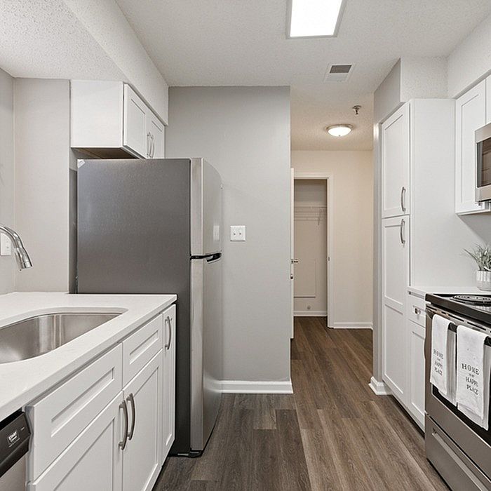 Modern kitchen with sleek stainless steel appliances, elegant white cabinetry, and warm hardwood floors.