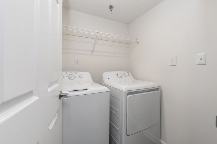 Sleek laundry room featuring modern washer and dryer set under a convenient wire shelf.