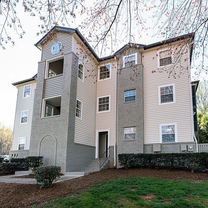 Charming modern apartment building with elegant architecture, surrounded by lush greenery, ideal for serene living.