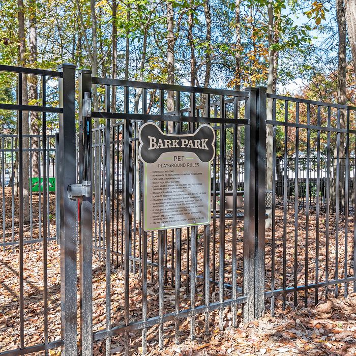 Inviting Bark Park pet playground surrounded by lush trees and secure fencing, perfect for outdoor fun with your furry friends.