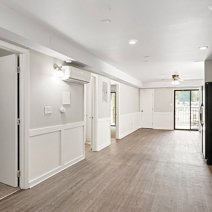 Bright open floor plan featuring elegant wood flooring, modern lighting, and a spacious layout with large sliding glass doors leading to a balcony.